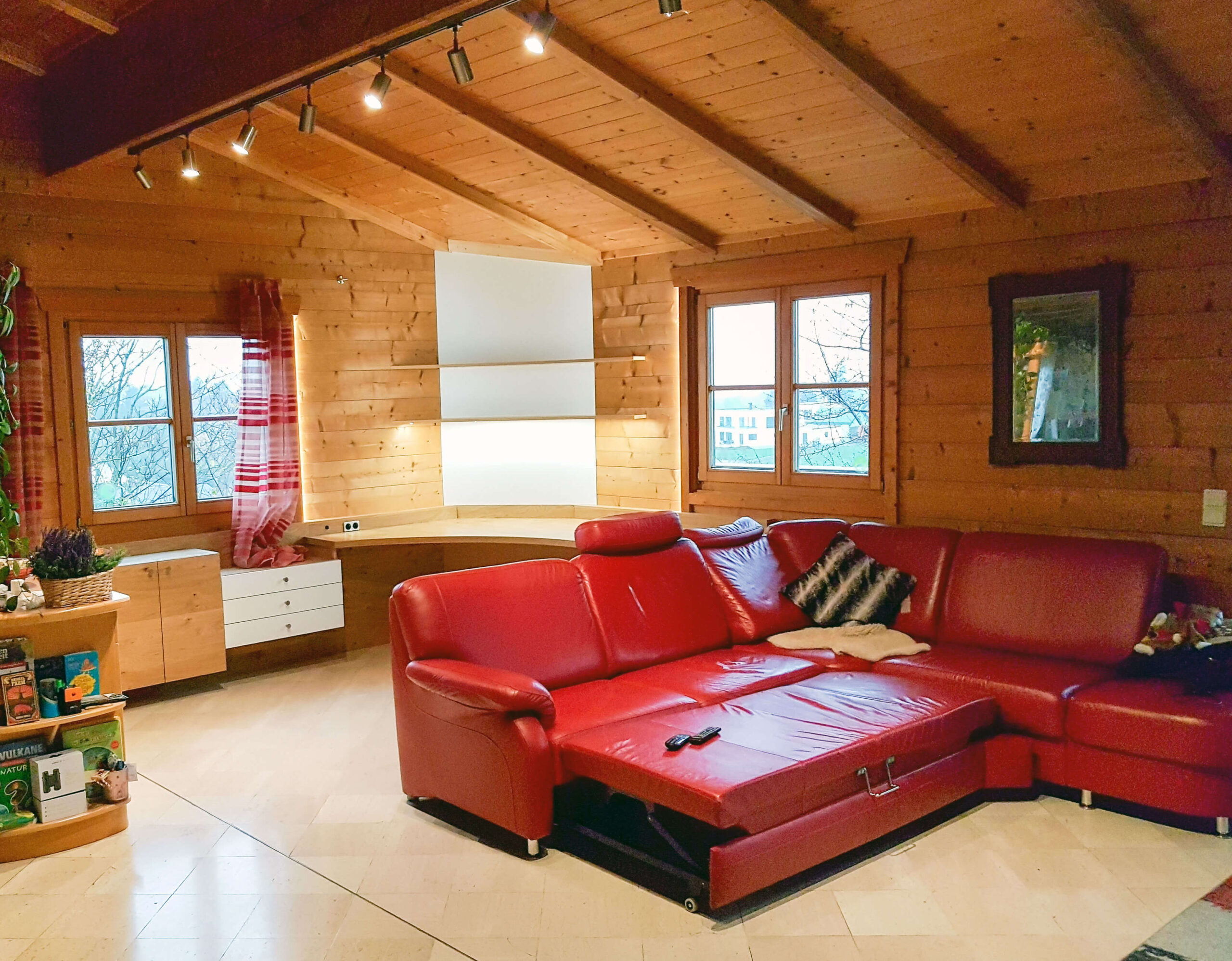 Arbeitsbereich, abgerundeter Schreibtisch, Schubladenelemente, offenes Regal, rote Couch