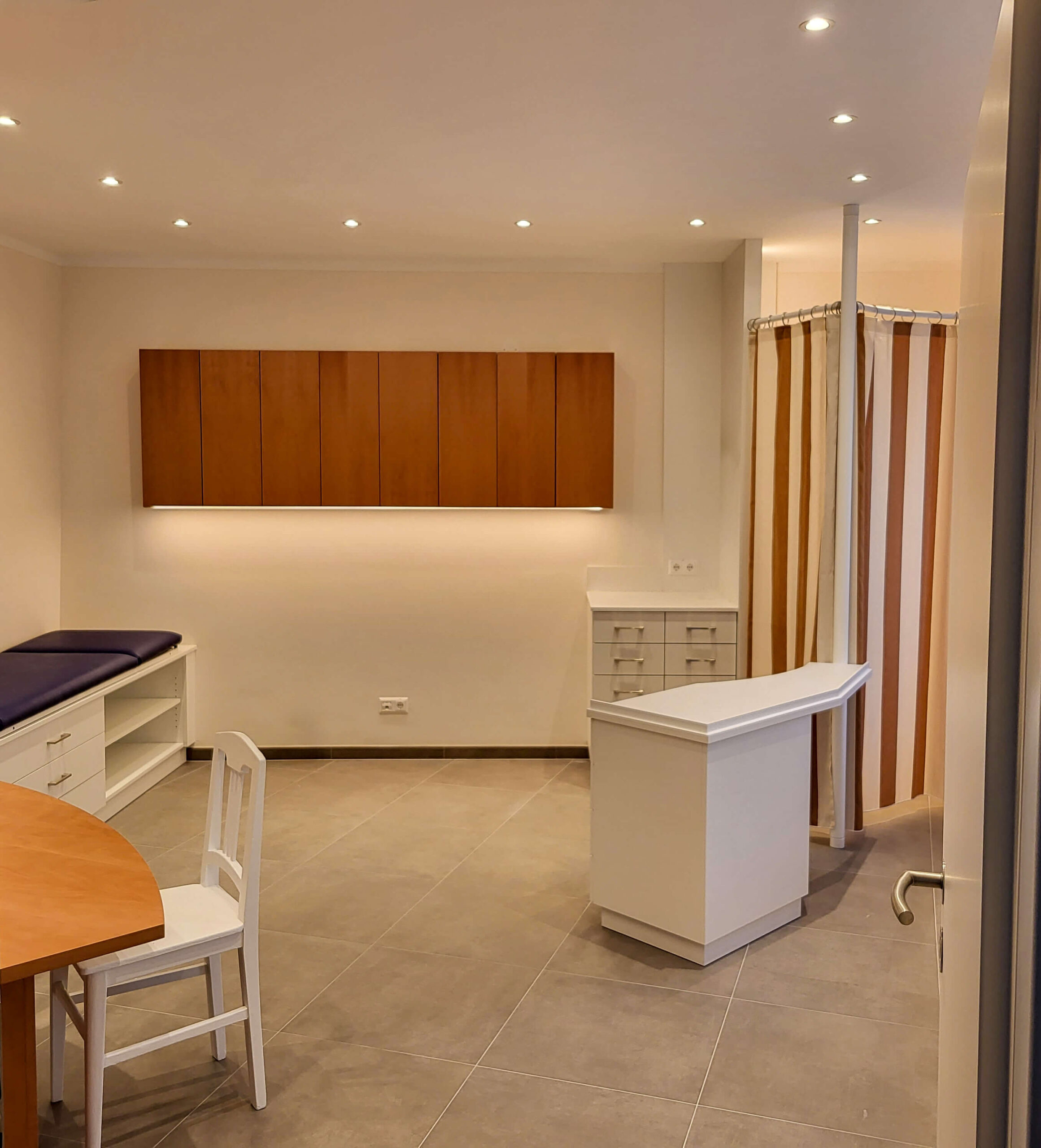Arztpraxis, Behandlungsraum, Liege, Schreibtisch, Oberschränke, Schubladenelemente, Vorhang