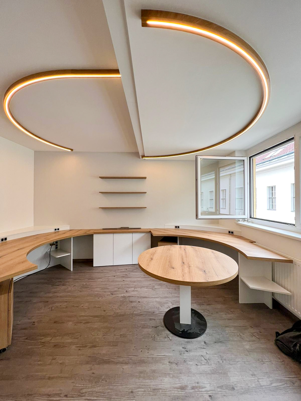 Büro, abgerundete Schreibtische, runder Besprechungstisch, beleuchtetes Deckenelement