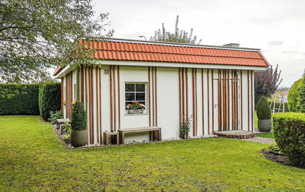 Gartenhaus, Holzpaneele an der Wand, Sitzbank und Hocker