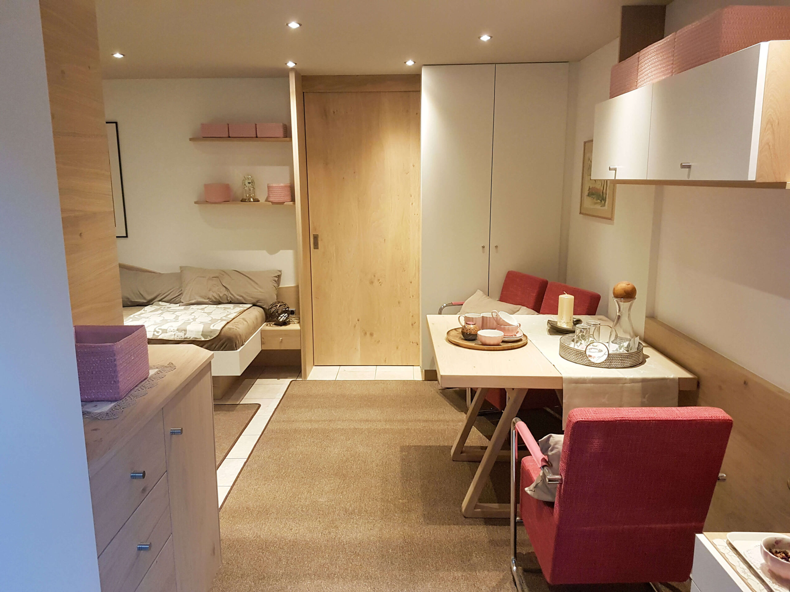 kleine Wohnung mit Schränken kleiner Tisch mit Stühlen, Glastür, Bett, Holzschiebetür