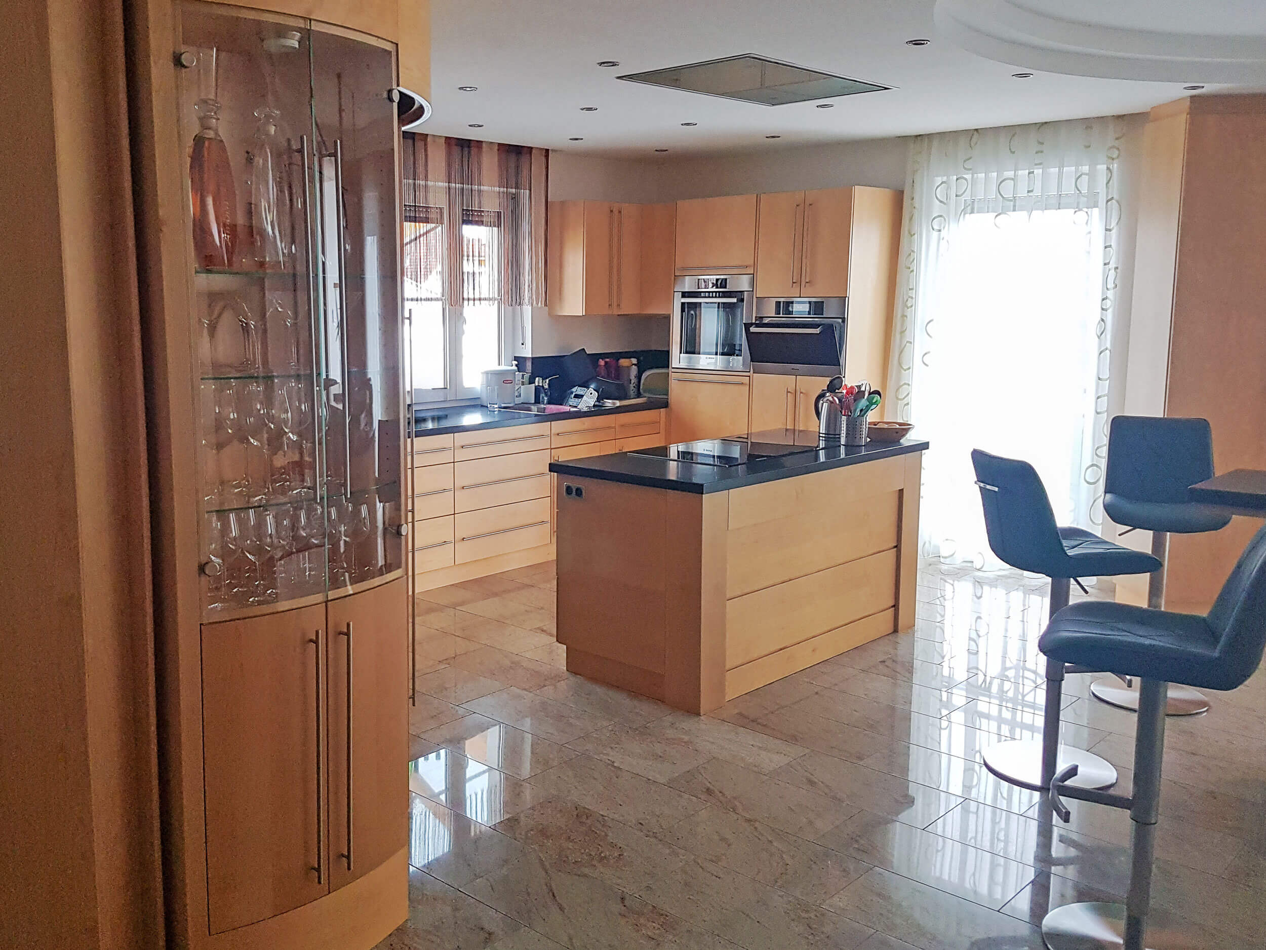 Küche mit Kochinsel in Holztönen und Glasschrank