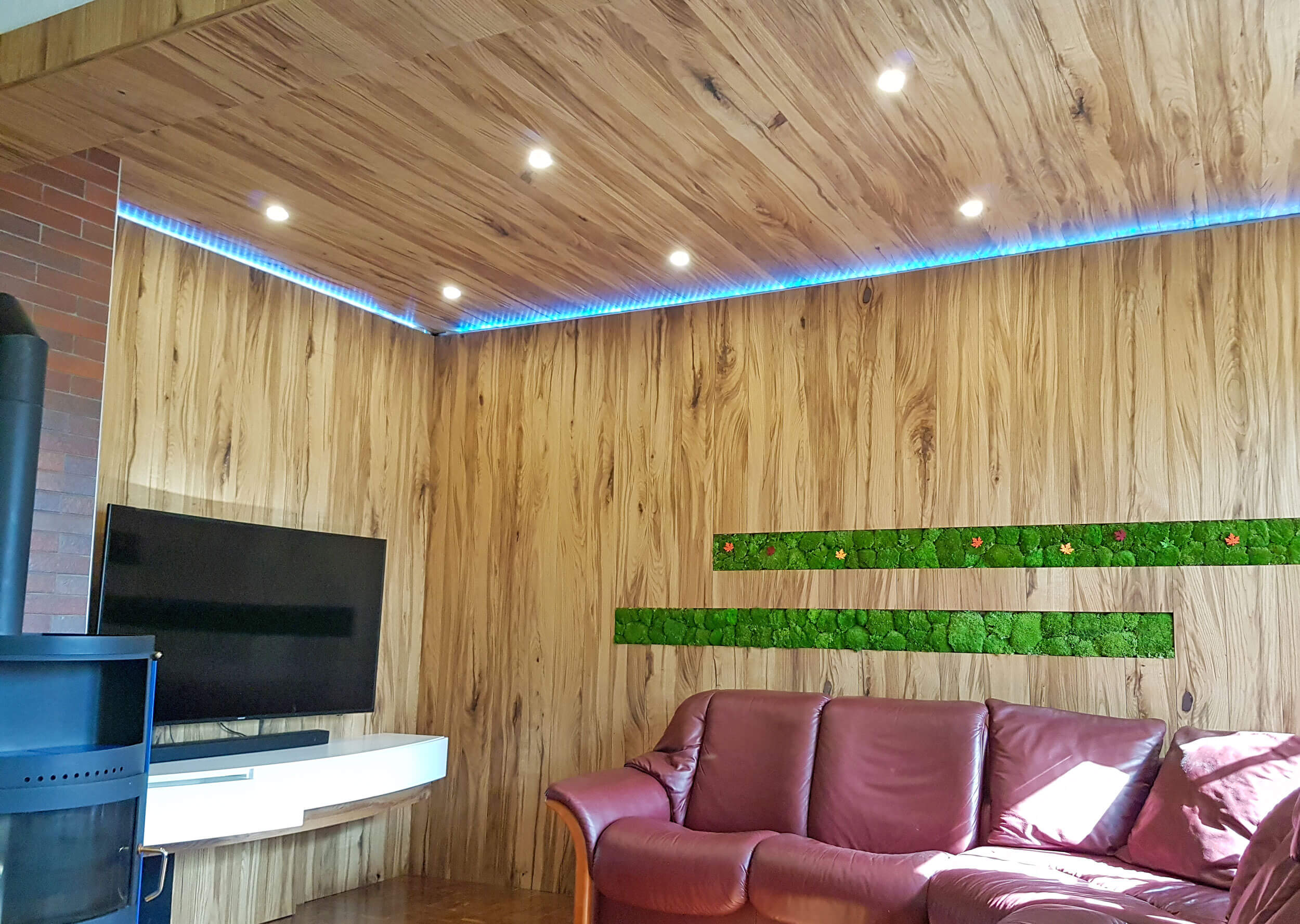 Sitzecke mit TV, mit Holz verbaut, integriertes Lichtband, in Holzwand Mooselemente eingearbeitet