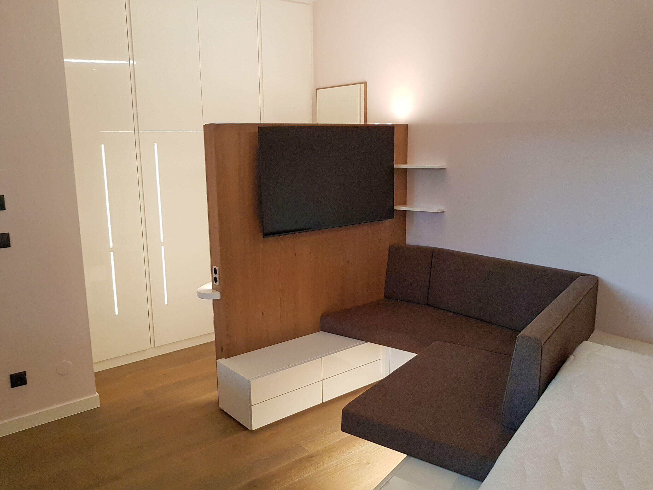 Schlafzimmer, abgetrennte Sitzecke mit TV, dahinter Schrankwand