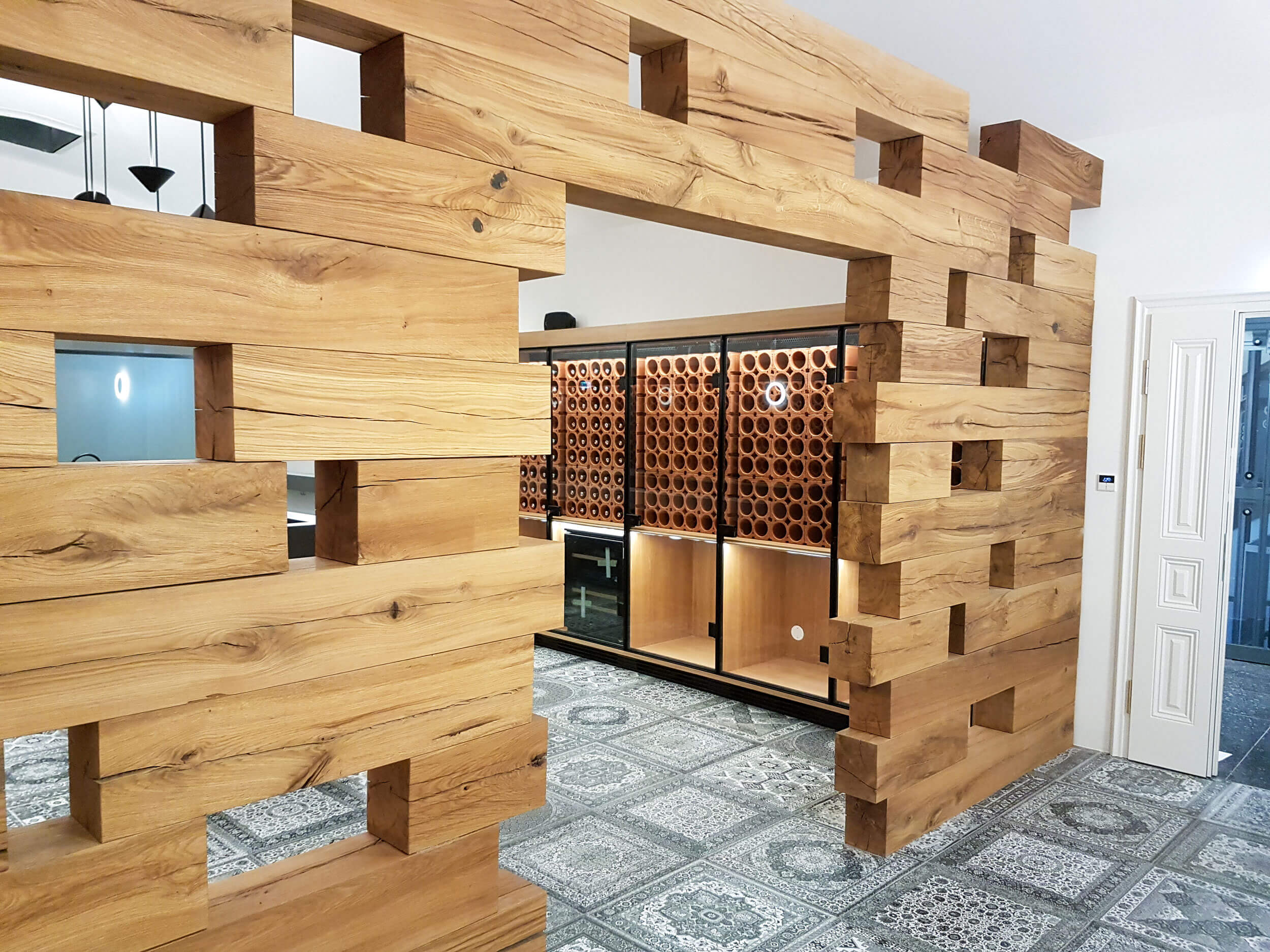 Weinverkostraum mit Design-Holzelementen, Theke in der Mitte aus Stein, Kühlschränke für Weinflaschen, Glasschiebetür