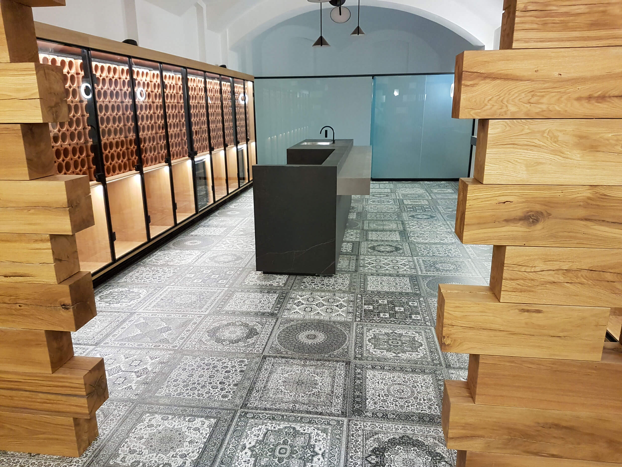 Weinverkostraum mit Design-Holzelementen, Theke in der Mitte aus Stein, Kühlschränke für Weinflaschen, Glasschiebetür